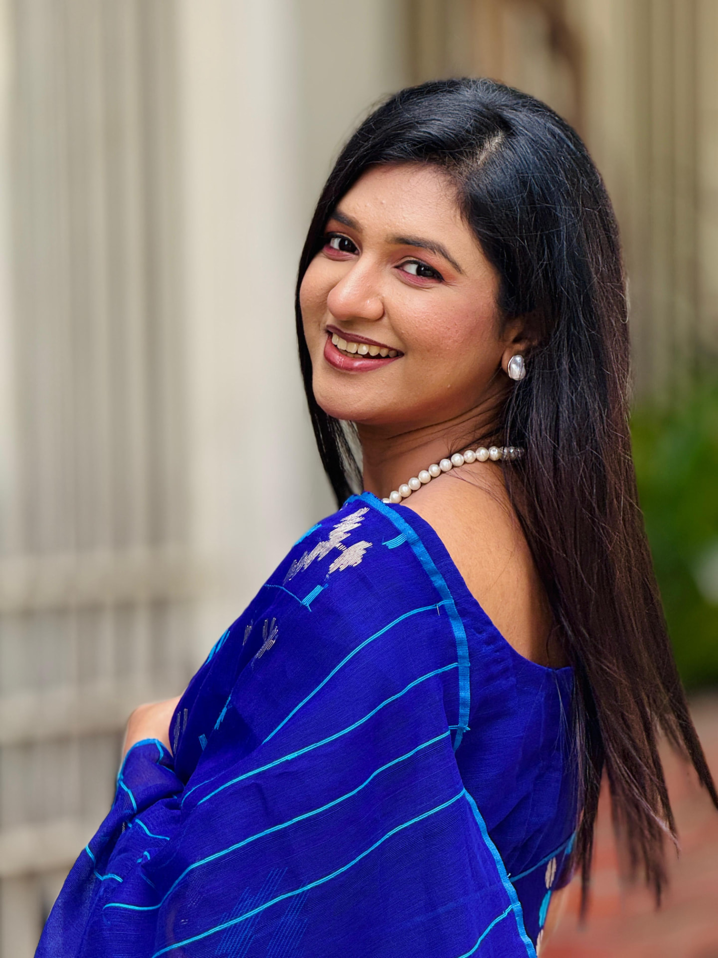 Portrait of Sanjida Rahman in a blue saree smiling over her shoulder