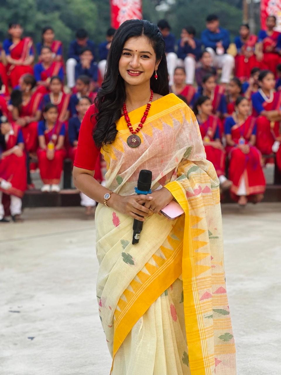 Sanjida Rahman hosting an outdoor school programme with students gathered behind her